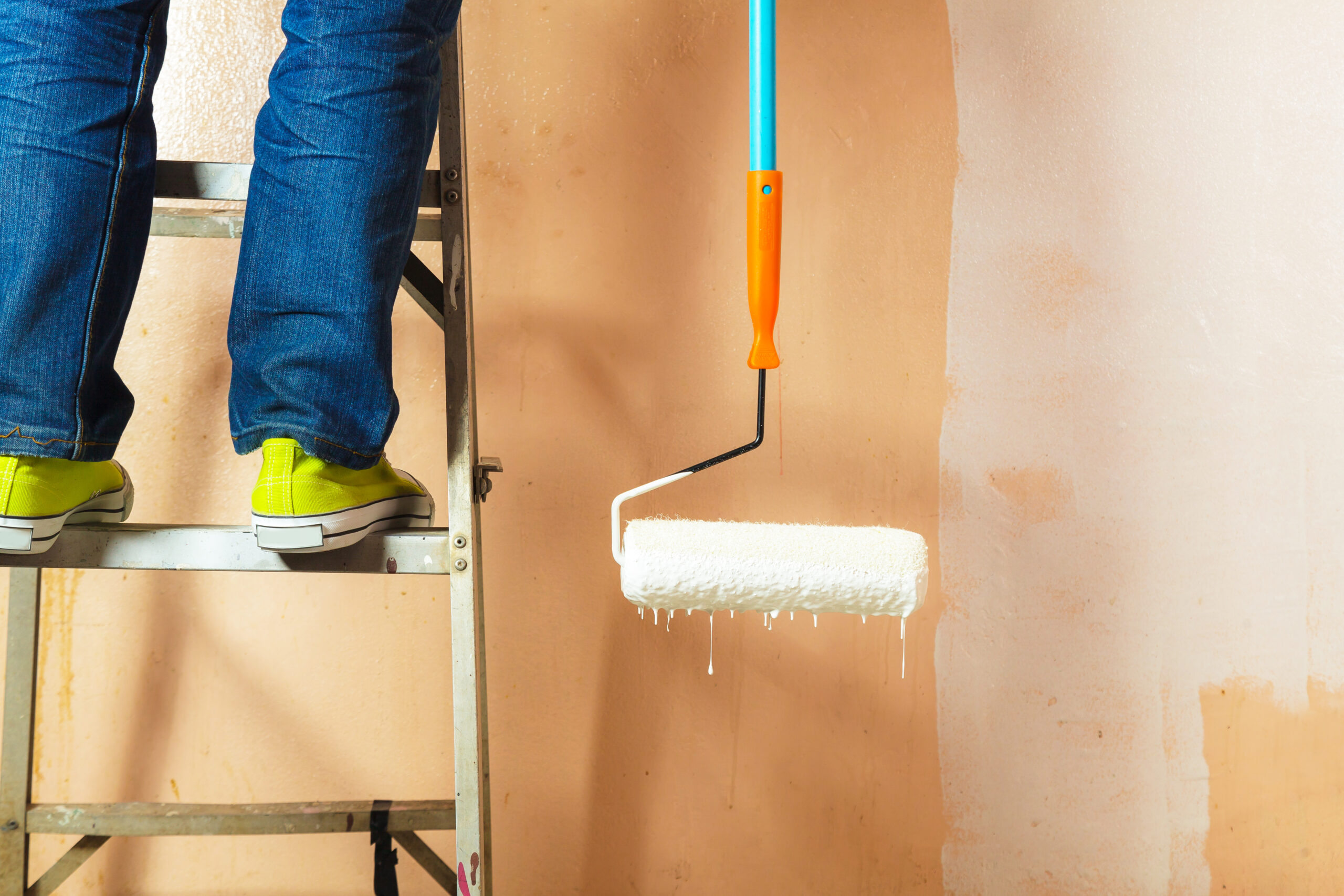 Painter painting the walls white in house