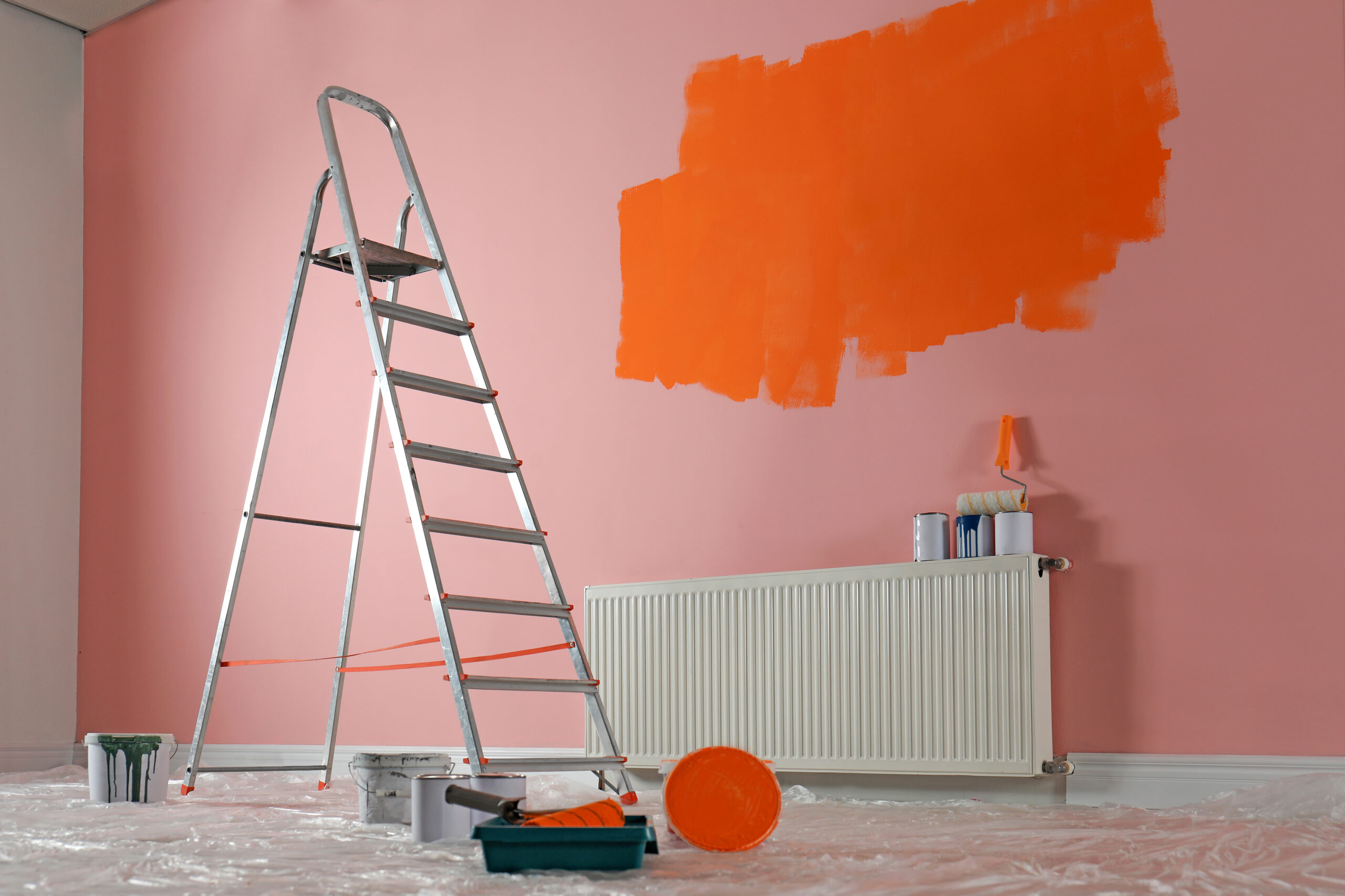 Stepladder and painting tools near wall in empty room