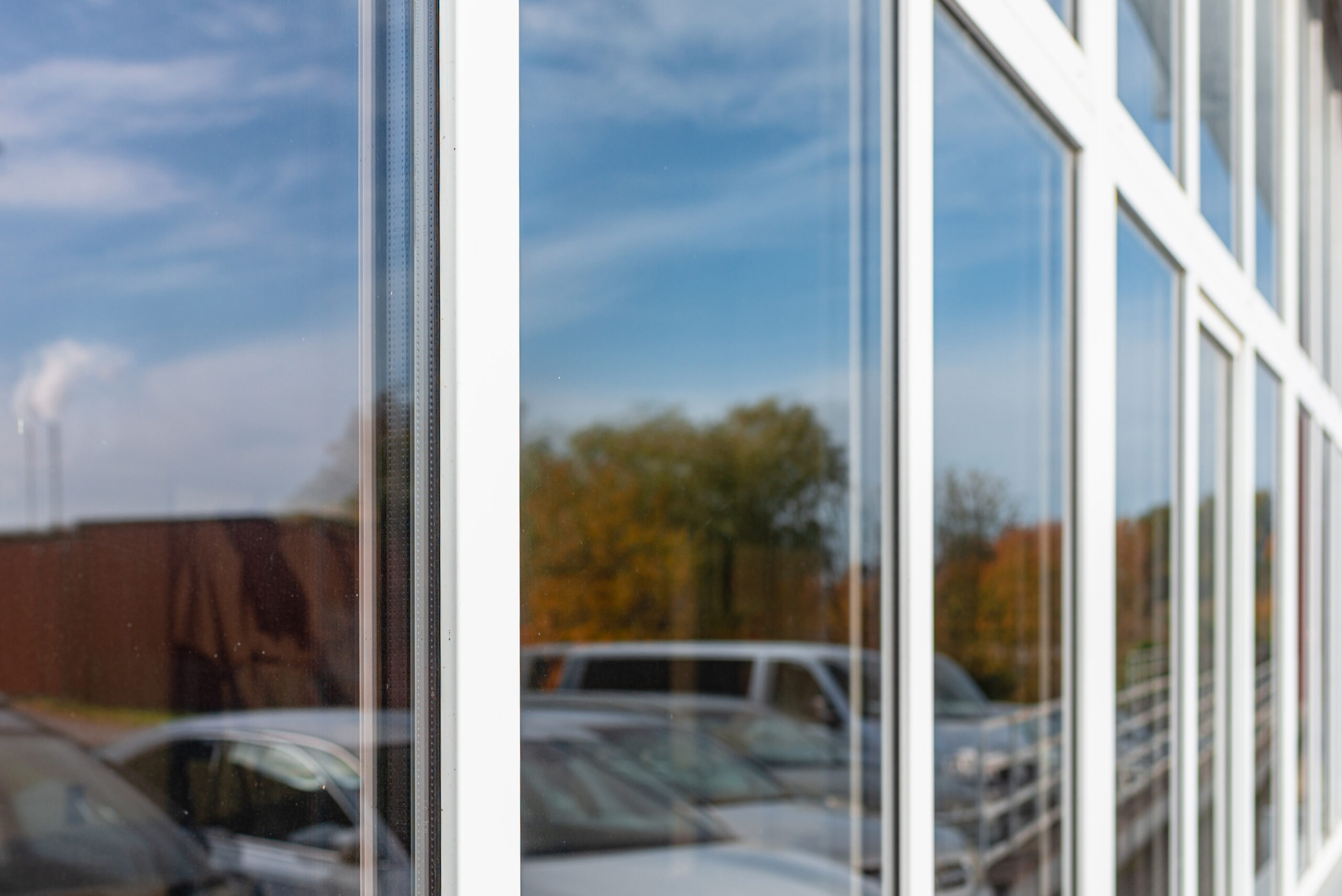 Office building or apartment house with cars parking reflection on a cloudy summer day.Business background.Selective focus.